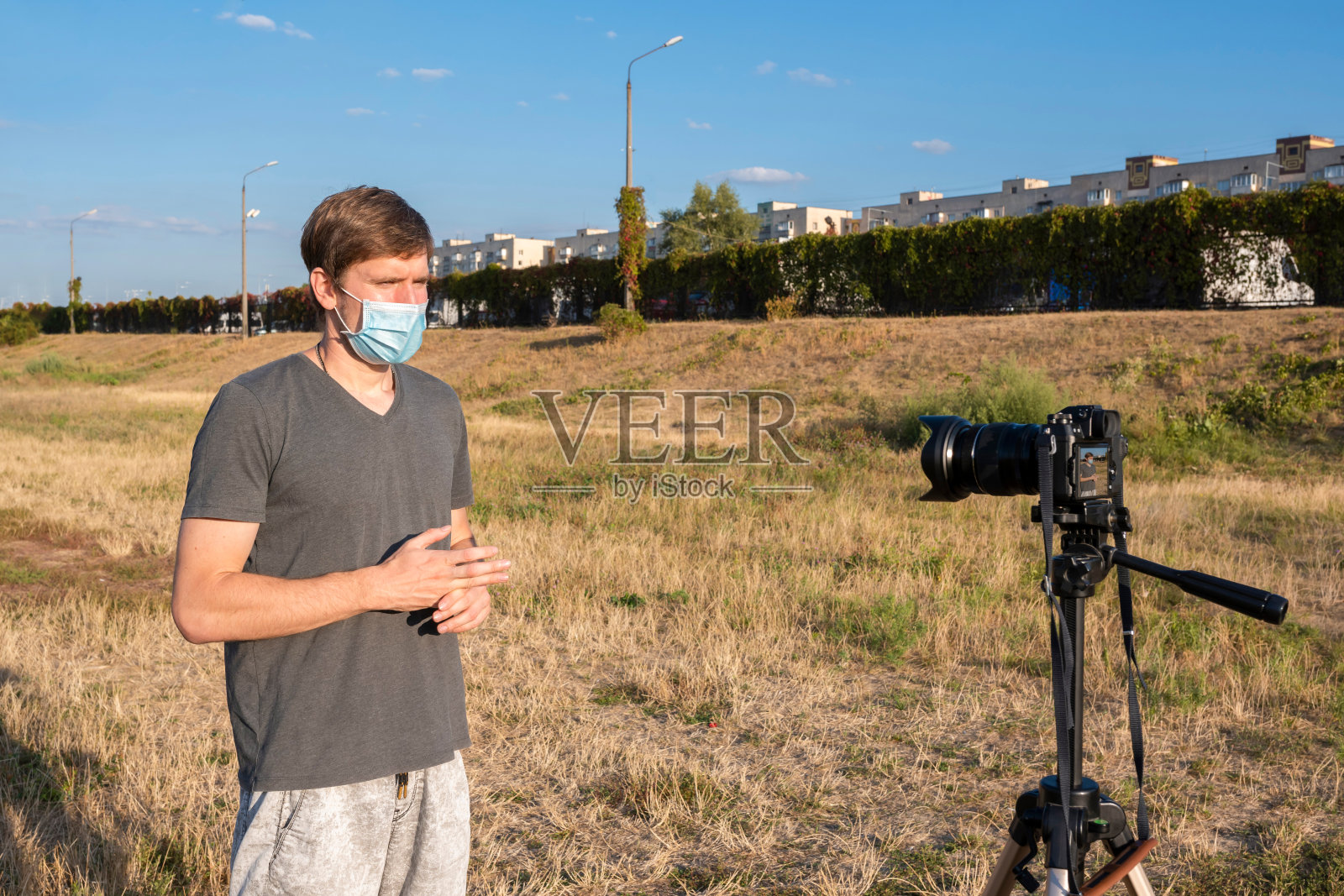 一名戴着医用口罩的男子正在为镜头写博客。在线沟通、咨询、培训、业务。距离生活方式的概念。照片摄影图片