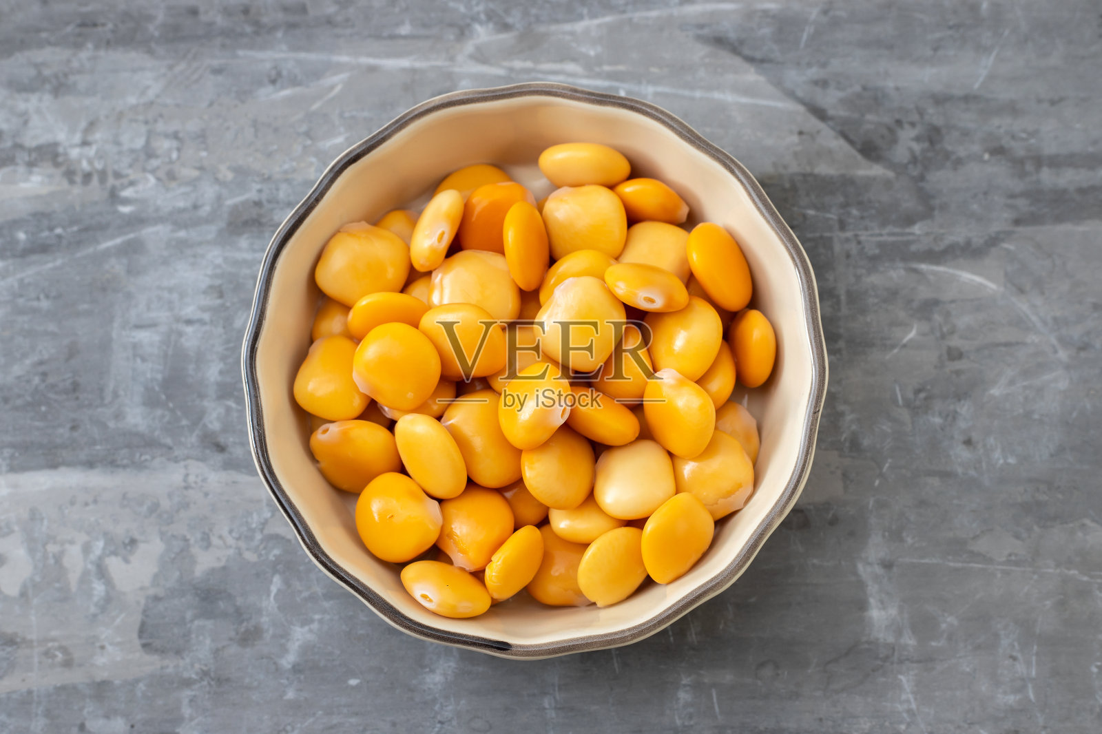 在陶瓷背景的浅棕色小碗里放盐羽扇豆照片摄影图片