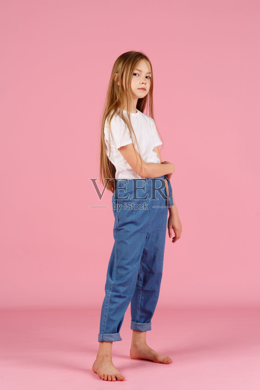 一个7岁的小女孩，穿着一件白色的衬衫，在粉红色的背景下，快乐和幸福的情绪。本空间照片摄影图片