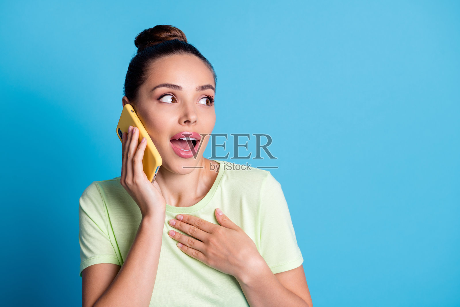 她的特写肖像，她漂亮的，迷人的，可爱的，迷人的，开朗的女孩在电话里和朋友讨论新闻孤立的，明亮的，生动的，闪亮的，充满活力的蓝色背景照片摄影图片