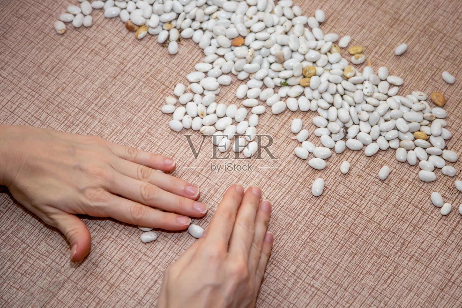 女人的手在厨房的桌子上挑选和清洗豆子。照片摄影图片