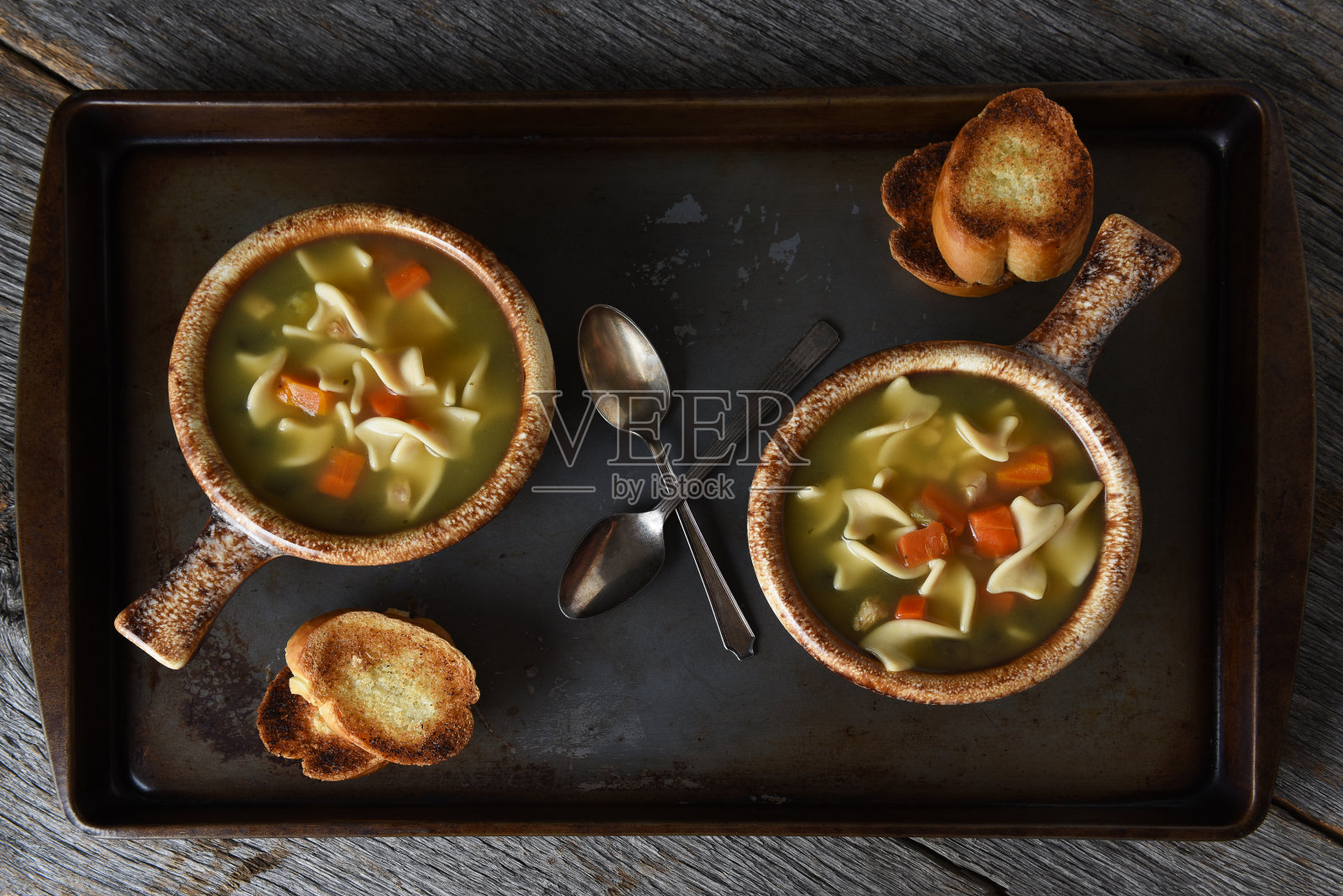 两碗鸡汤面，一份法式长棍大蒜吐司和一勺照片摄影图片