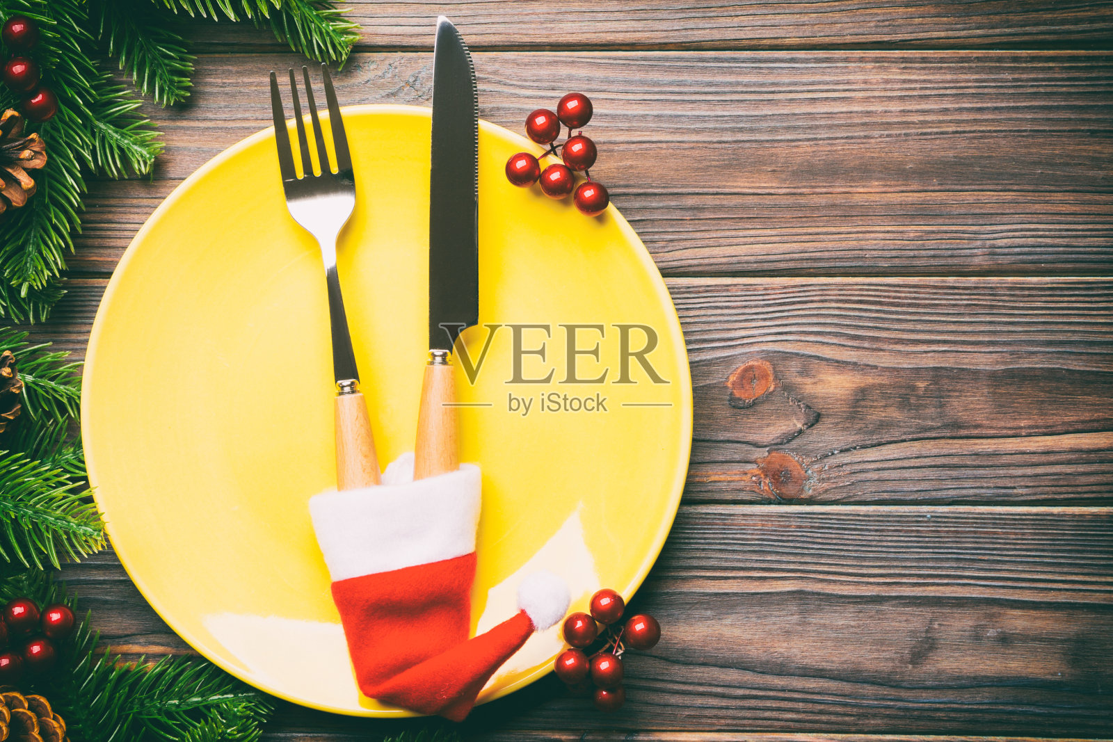 木制背景上的圣诞晚餐俯视图。盘子，器具，冷杉树和节日装饰与复制空间。新年时间概念照片摄影图片