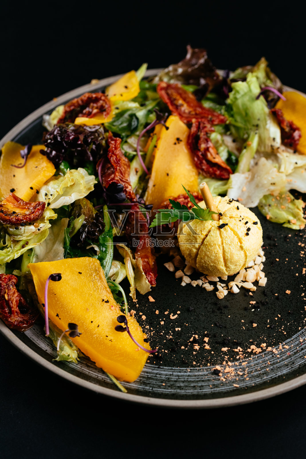 秋天的南瓜沙拉和晒干的番茄在黑色的背上照片摄影图片