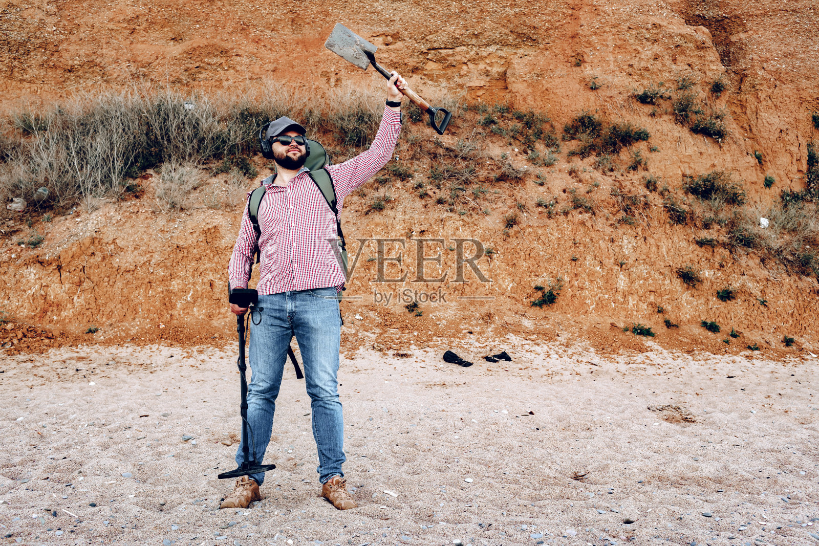 拿着金属探测器的男性在海滩上发现了一些东西照片摄影图片