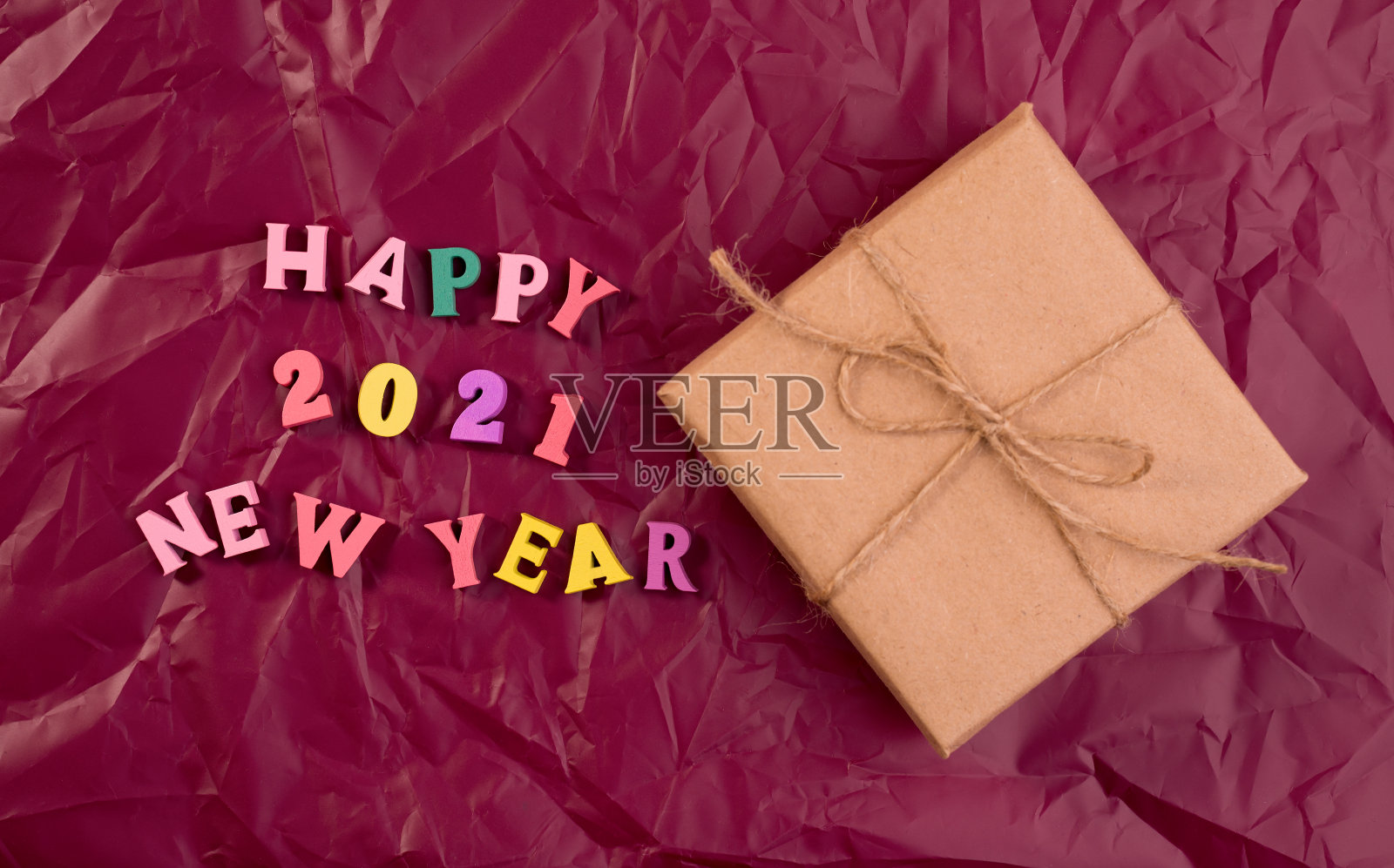 新年贺词木制字母，在紫色皱包装纸和工艺礼品盒。适合做极简主义的贺卡。照片摄影图片