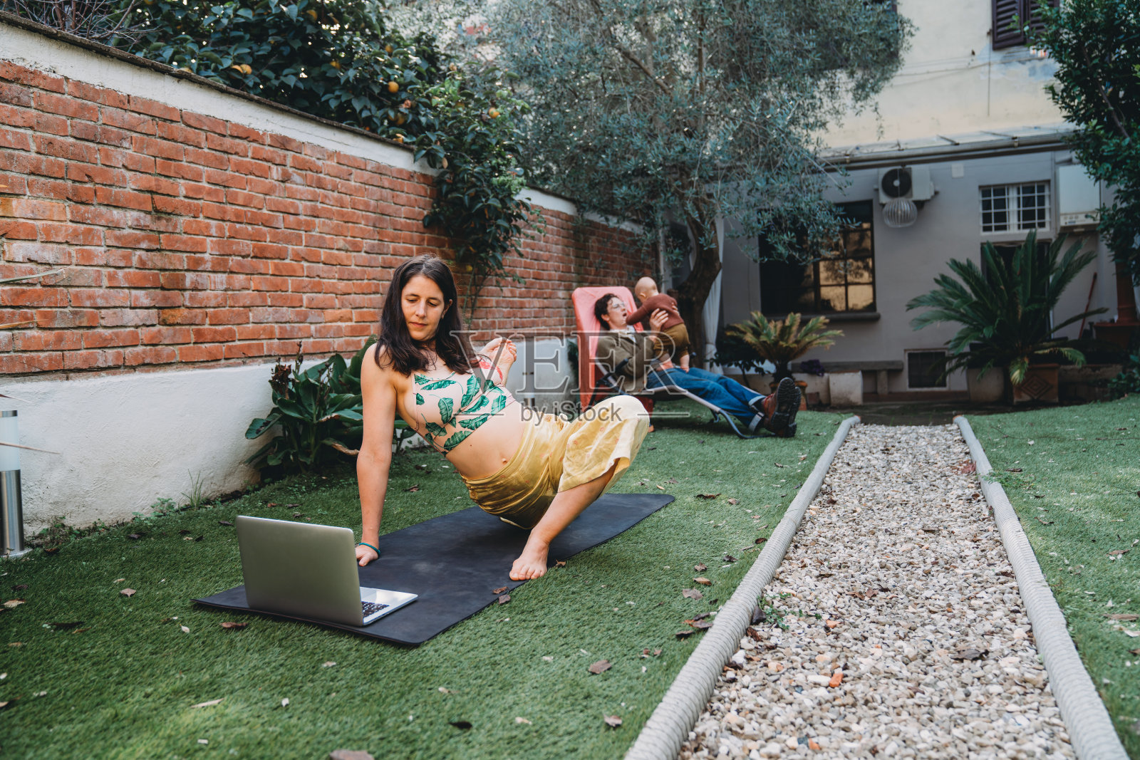有一个孩子的家庭花时间在后院-妈妈正在练习在线瑜伽课照片摄影图片