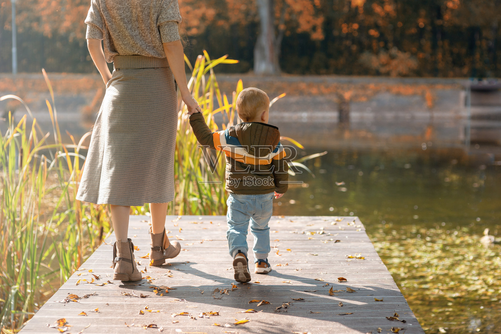 妈妈和小儿子正沿着池塘边的码头散步照片摄影图片