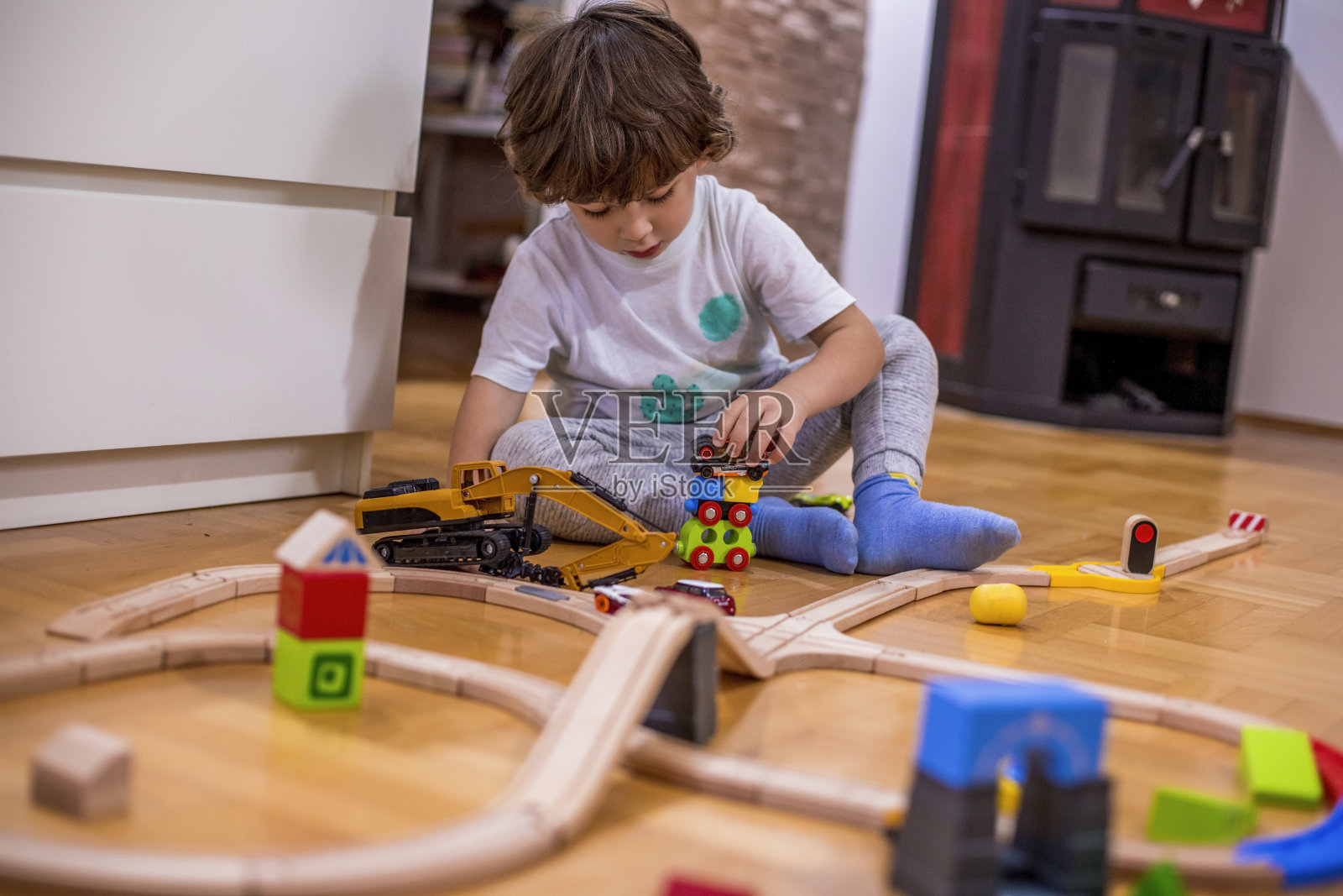 小男孩在玩火车玩具和塑料交通工具。照片摄影图片