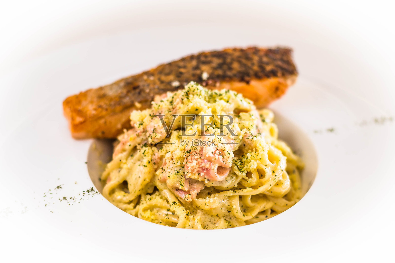烤三文鱼配意大利干酪意面、火腿、奶油沙司和碎奶酪照片摄影图片