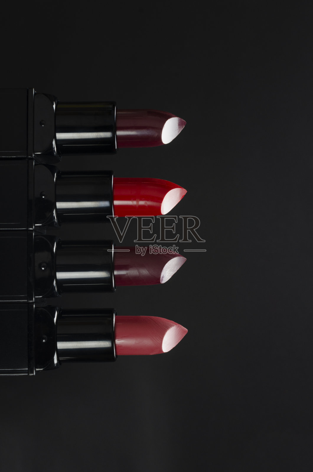 垂直的图像。红色，深紫色，粉红色的口红映衬着深色的背景照片摄影图片