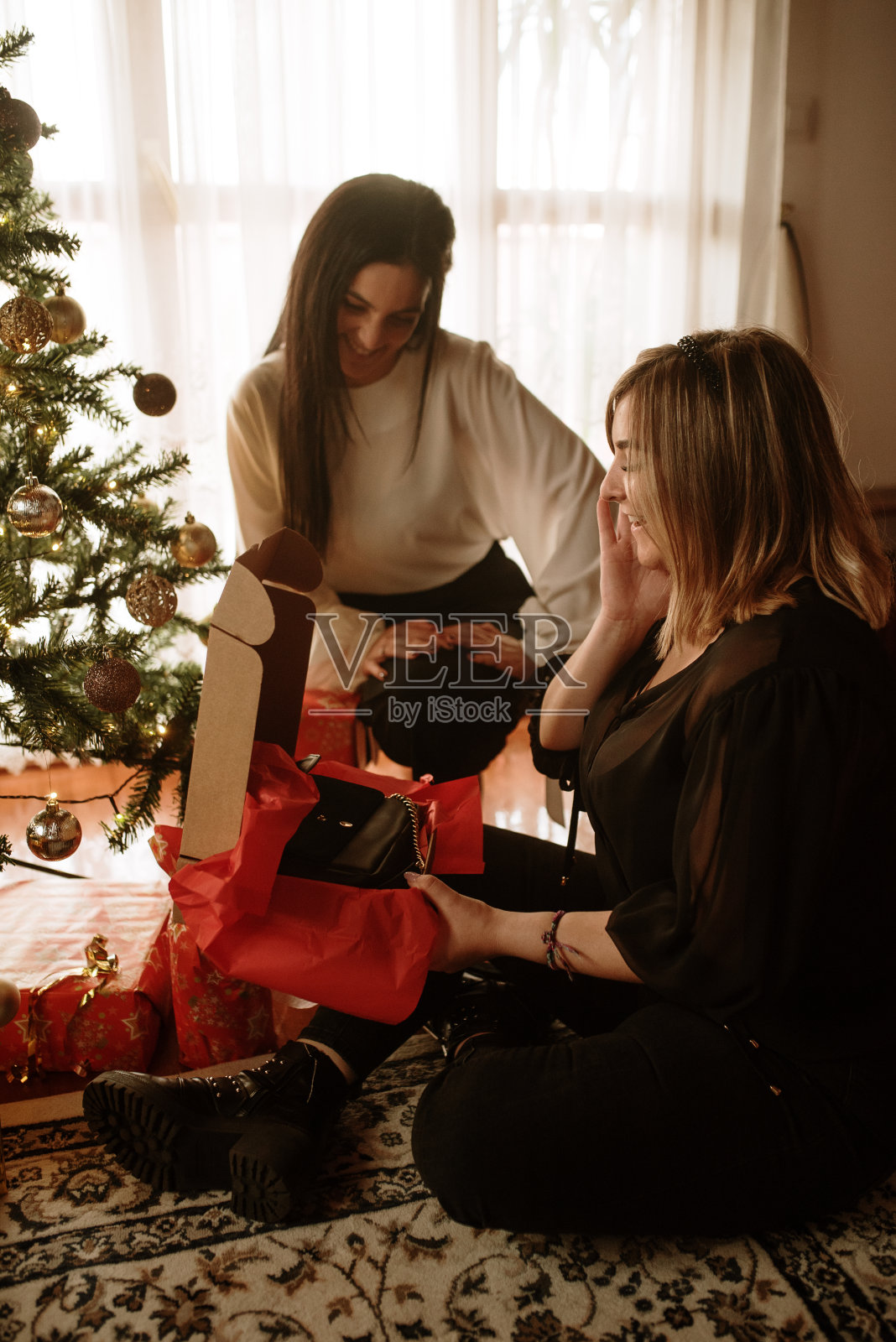 两个年轻女人正在打开圣诞礼物照片摄影图片