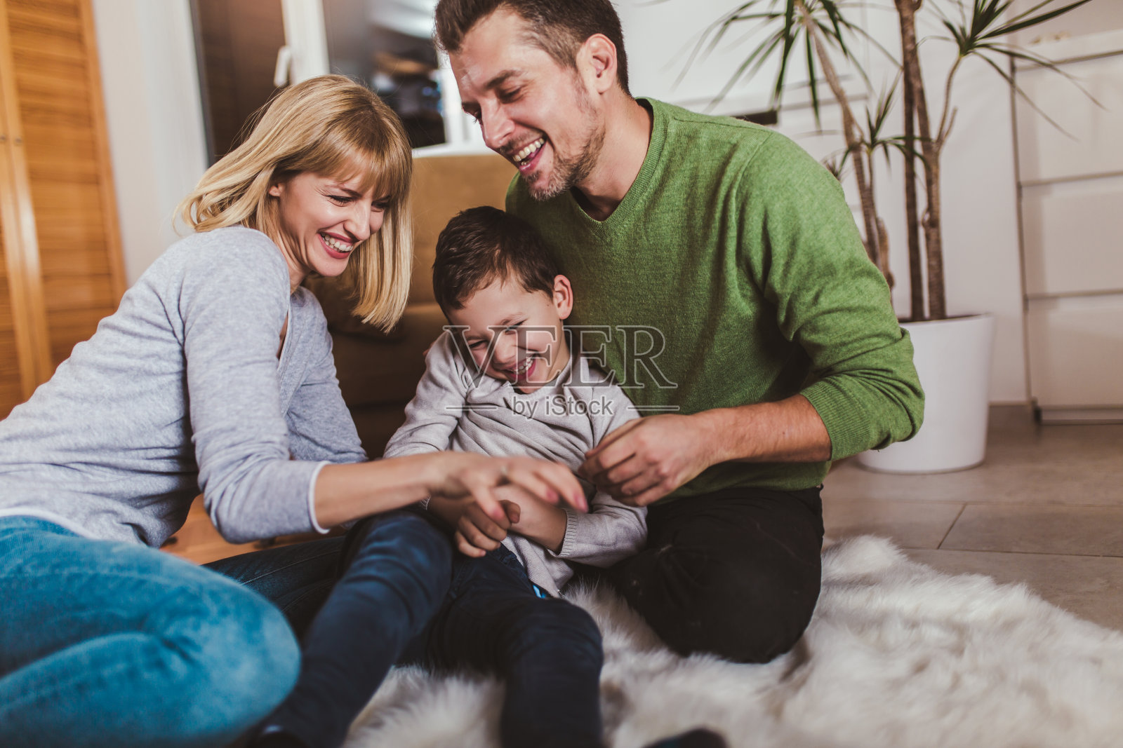 一家人坐在地板上，一起在家里玩。照片摄影图片