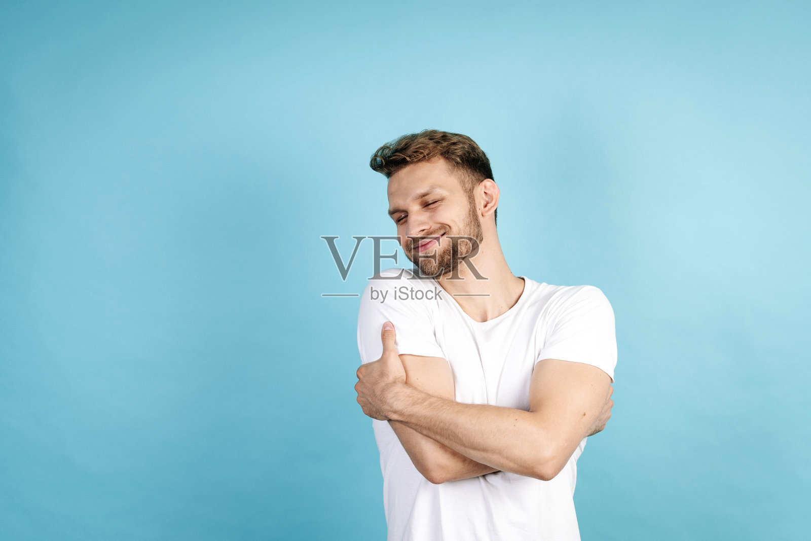 年轻人拥抱着自己，笑得很开心照片摄影图片