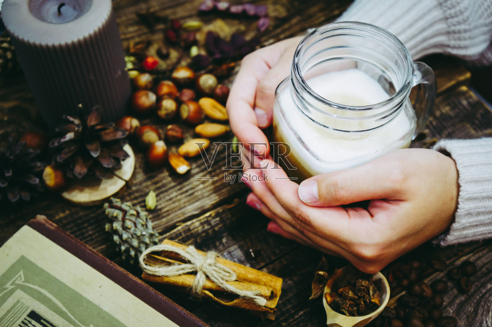 一个穿着暖和毛衣的女孩拿着一个装着拿铁咖啡的杯子照片摄影图片