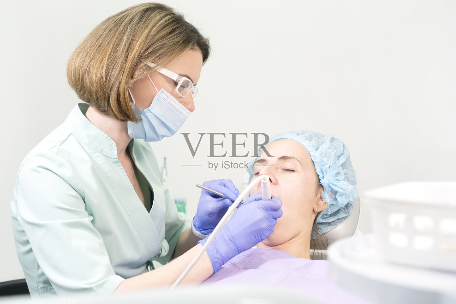 女牙医医生治疗牙齿的一个年轻女孩坐在椅子上照片摄影图片