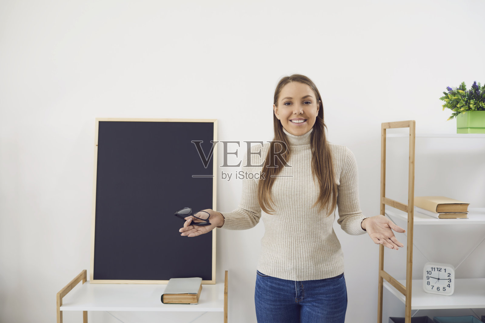 在线学习。一位戴着眼镜的老师微笑着走进教室的黑板上的摄像头视频聊天通话。照片摄影图片