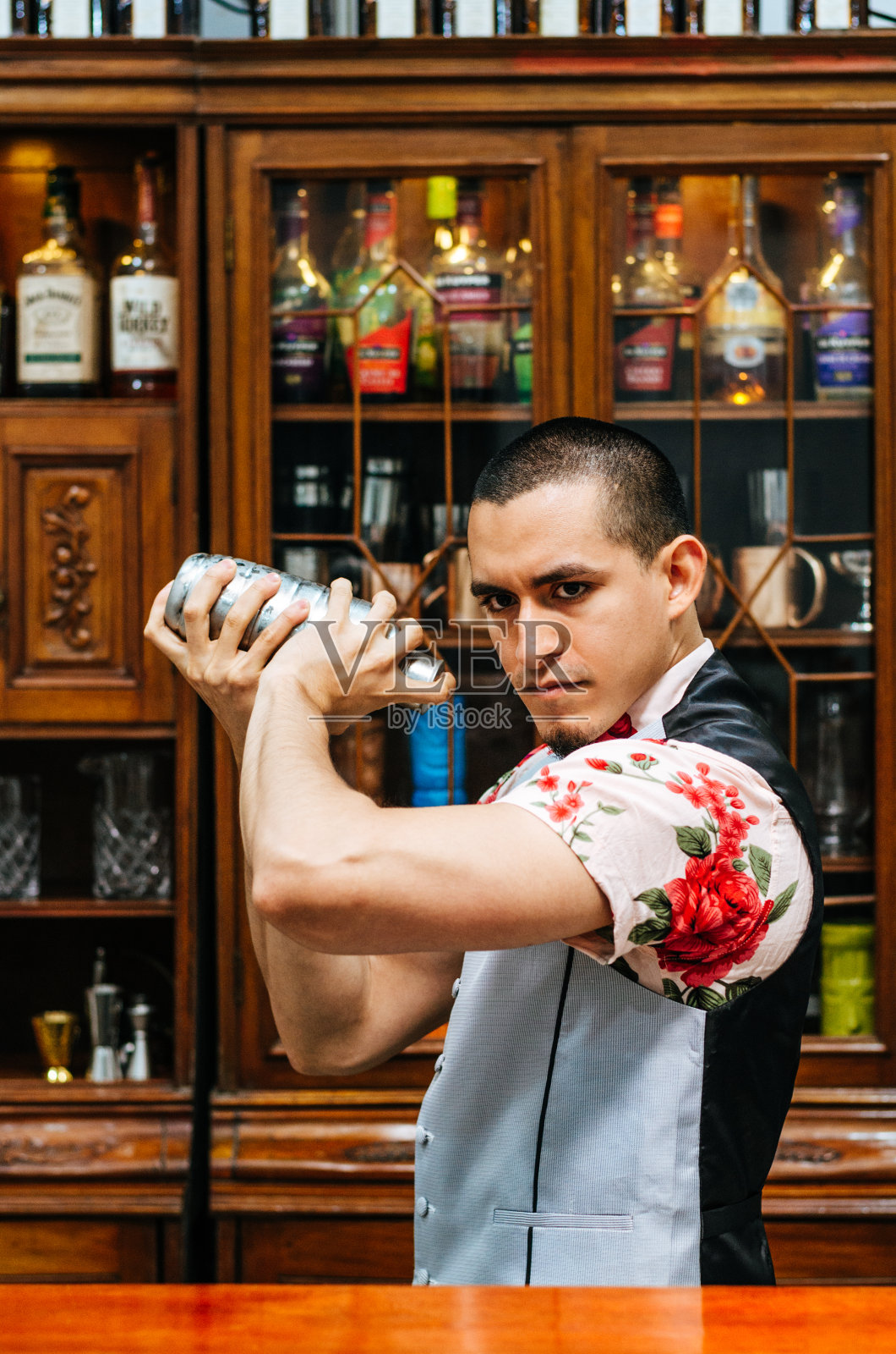 年轻英俊微笑的酒吧男招待在酒吧内部摇晃和调酒鸡尾酒。照片摄影图片