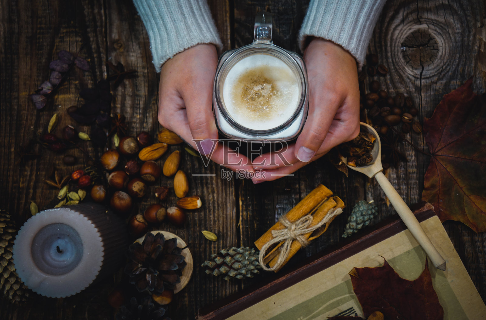 一个穿着暖和毛衣的女孩拿着一个装着拿铁咖啡的杯子照片摄影图片
