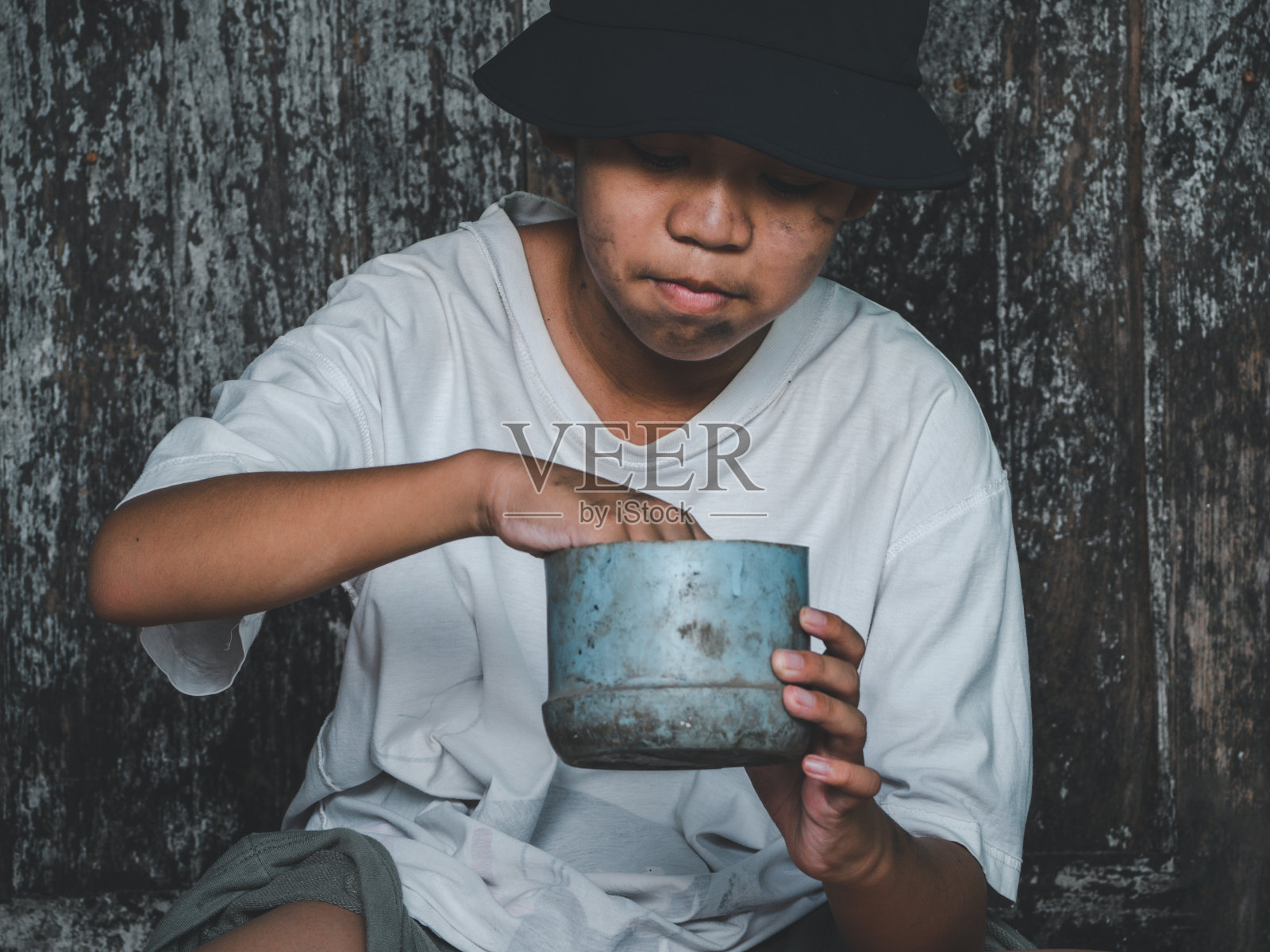 儿童或贫穷的无家可归者拿着塑料碗饥饿和请求帮助食物捐赠的旅行者在街道上的城市。身份不明的无家可归儿童在街上乞讨。避难所的概念。照片摄影图片