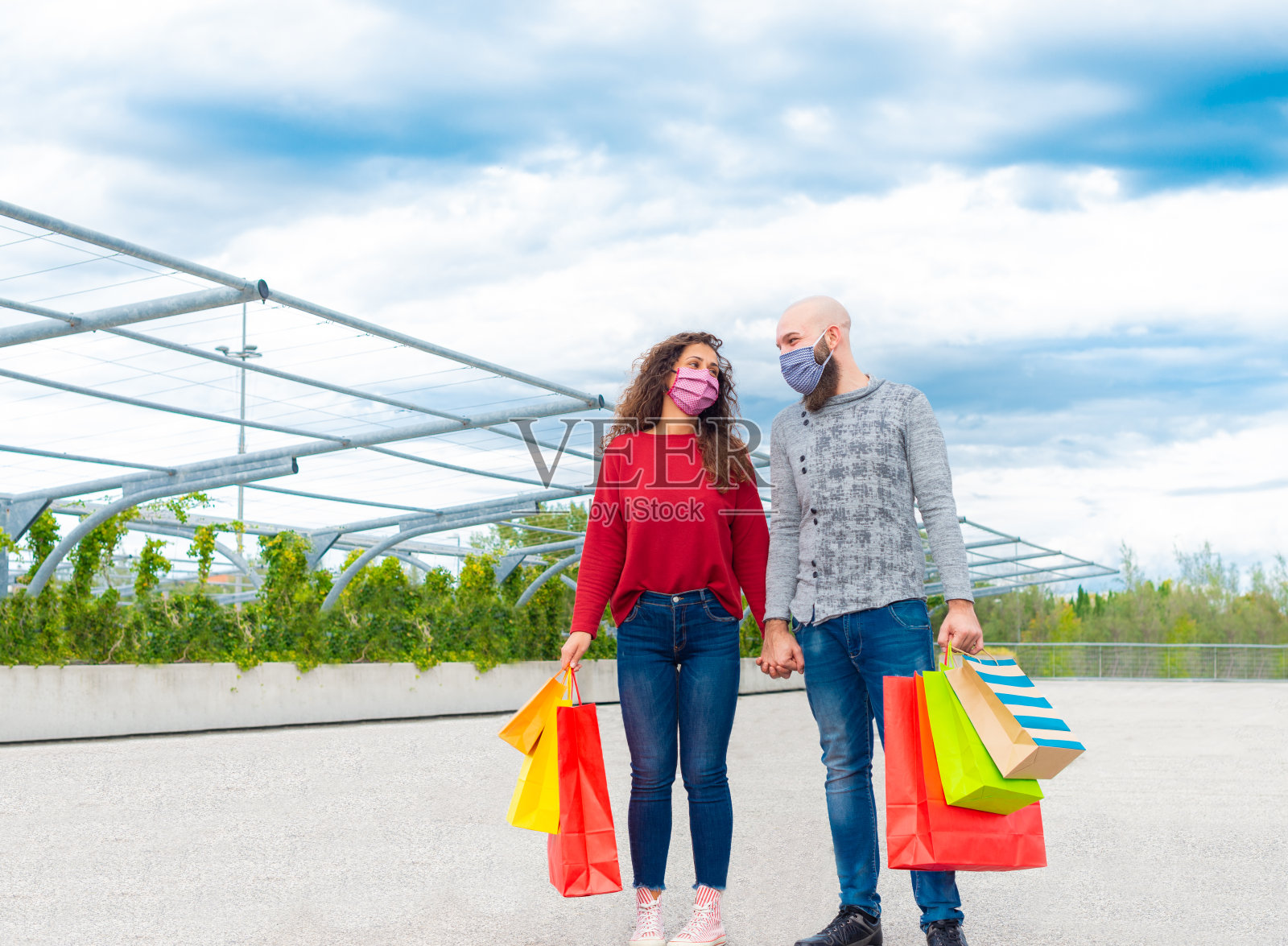 一男一女戴着口罩，在黑色星期五的大减价购物后手牵手。消费主义的概念和节日购物的乐趣照片摄影图片