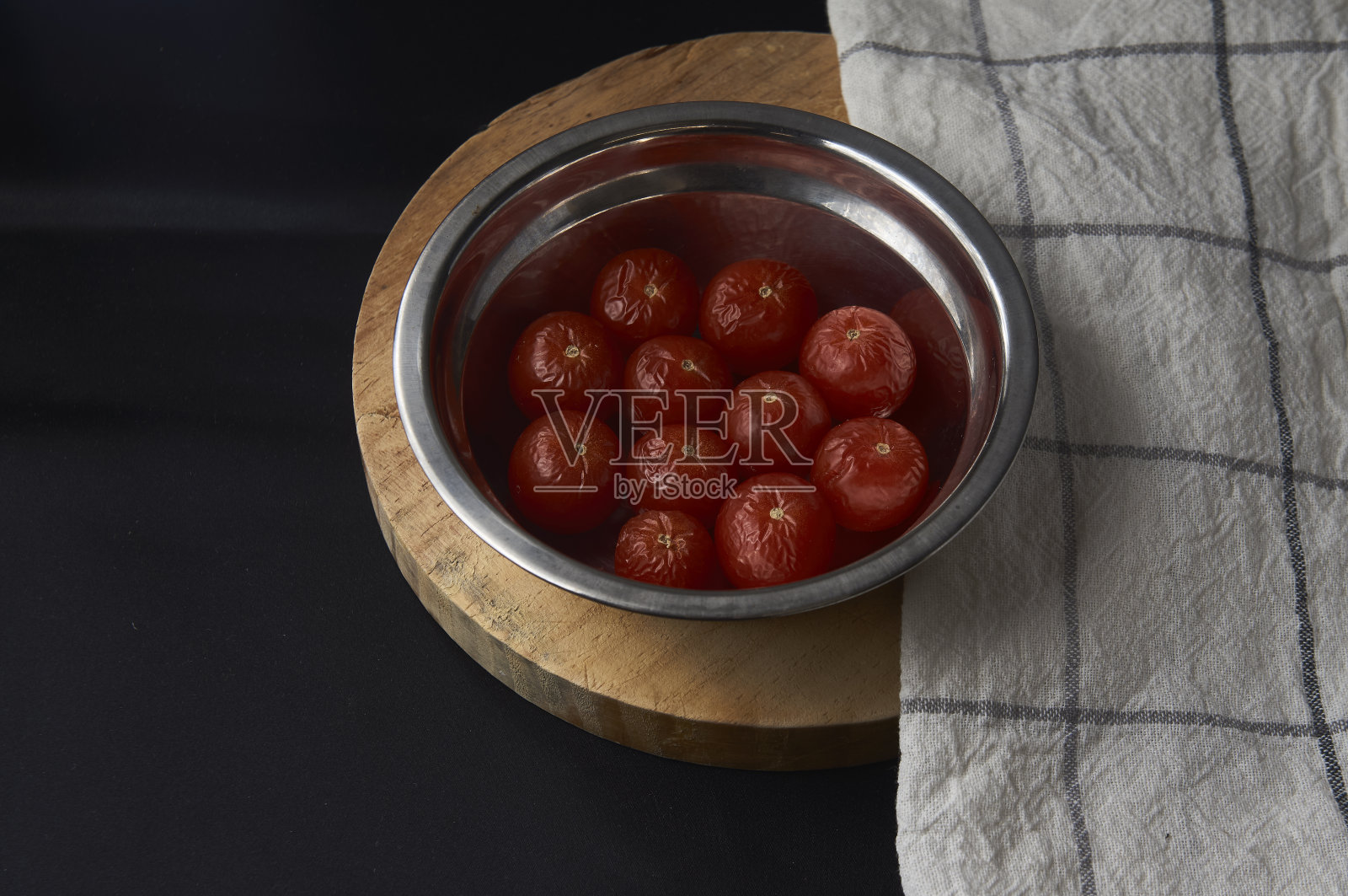 在切菜板和桌布上的一个金属碗里，成熟的樱桃番茄的特写镜头照片摄影图片