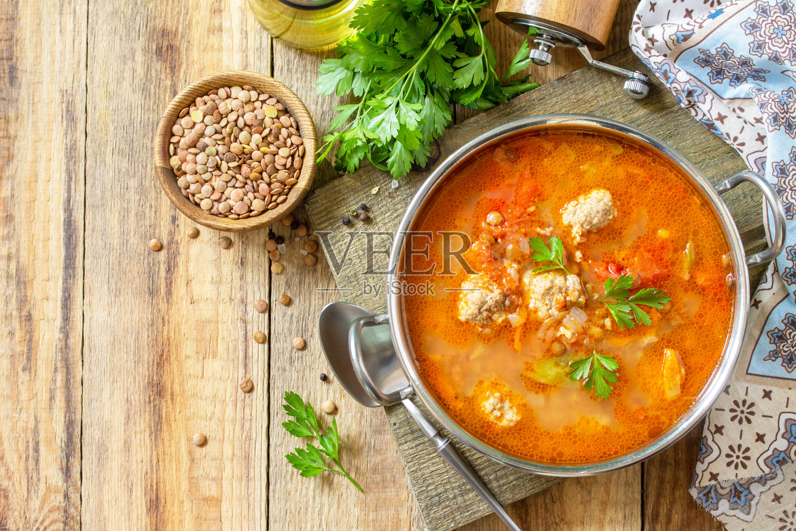 木桌上的番茄扁豆汤配肉丸和蔬菜。俯视图平铺背景。副本的空间。照片摄影图片