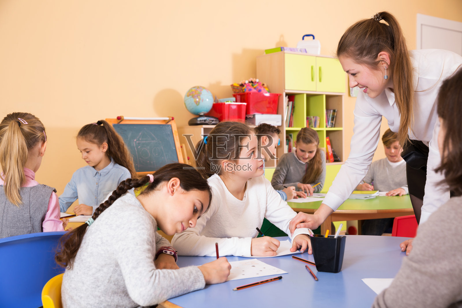 男孩和女孩坐着，老师帮助画画照片摄影图片