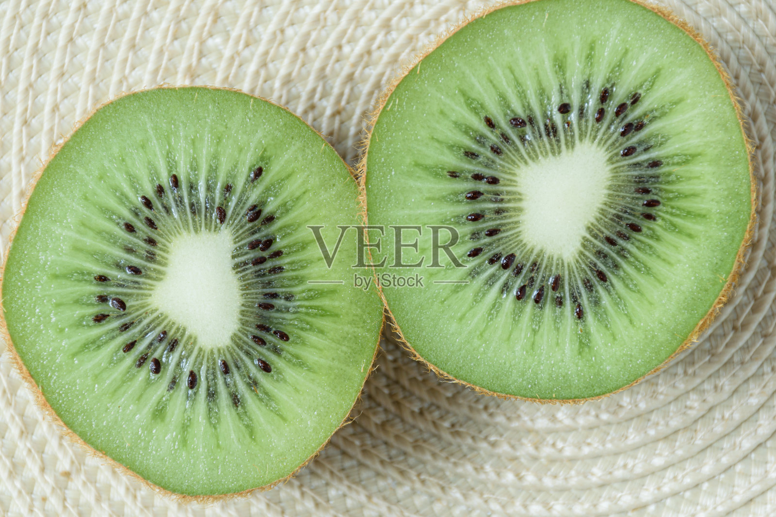两片猕猴桃放在草垫上，呈圆形。照片摄影图片