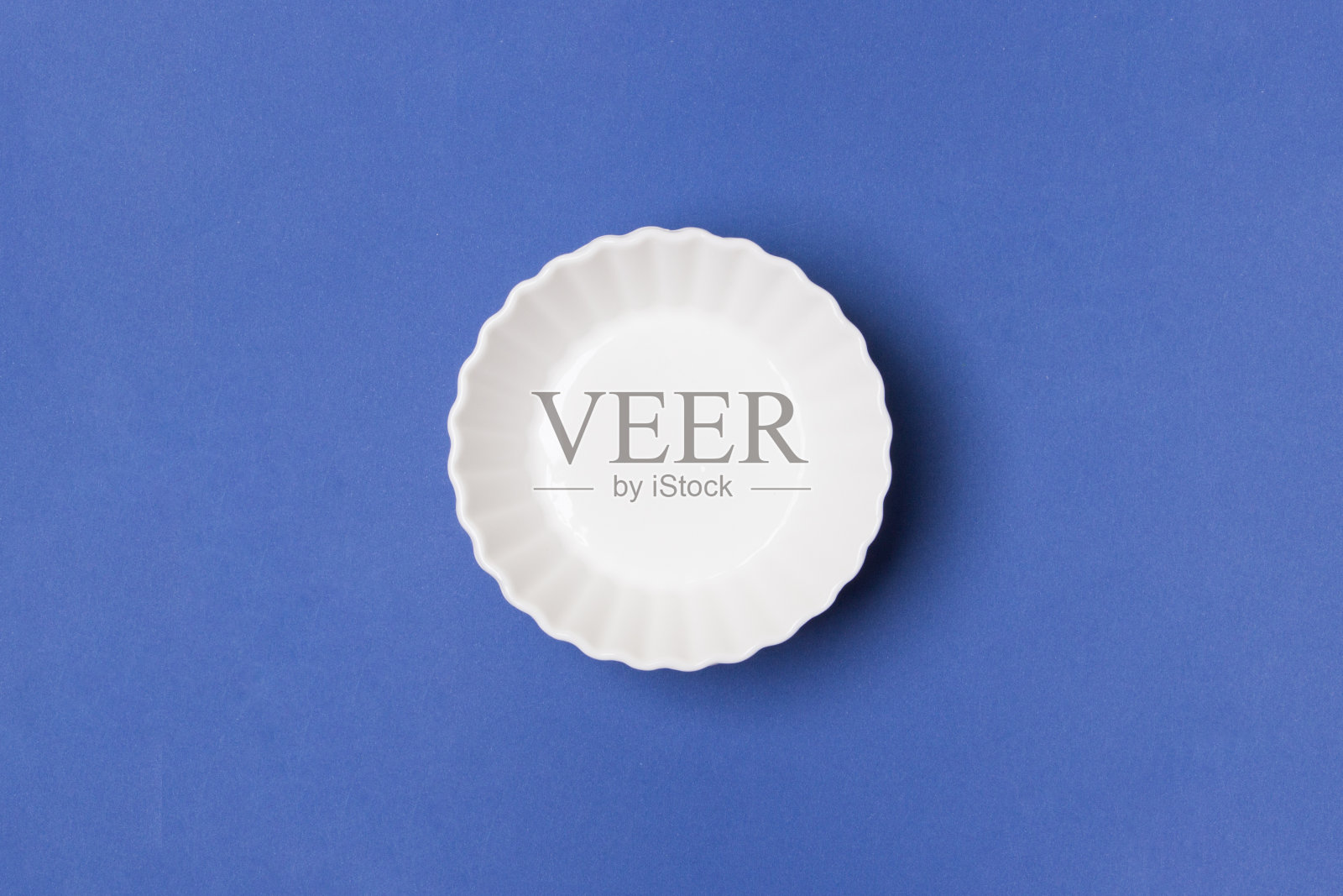 空白的白色盘子在蓝色的纸背景照片摄影图片