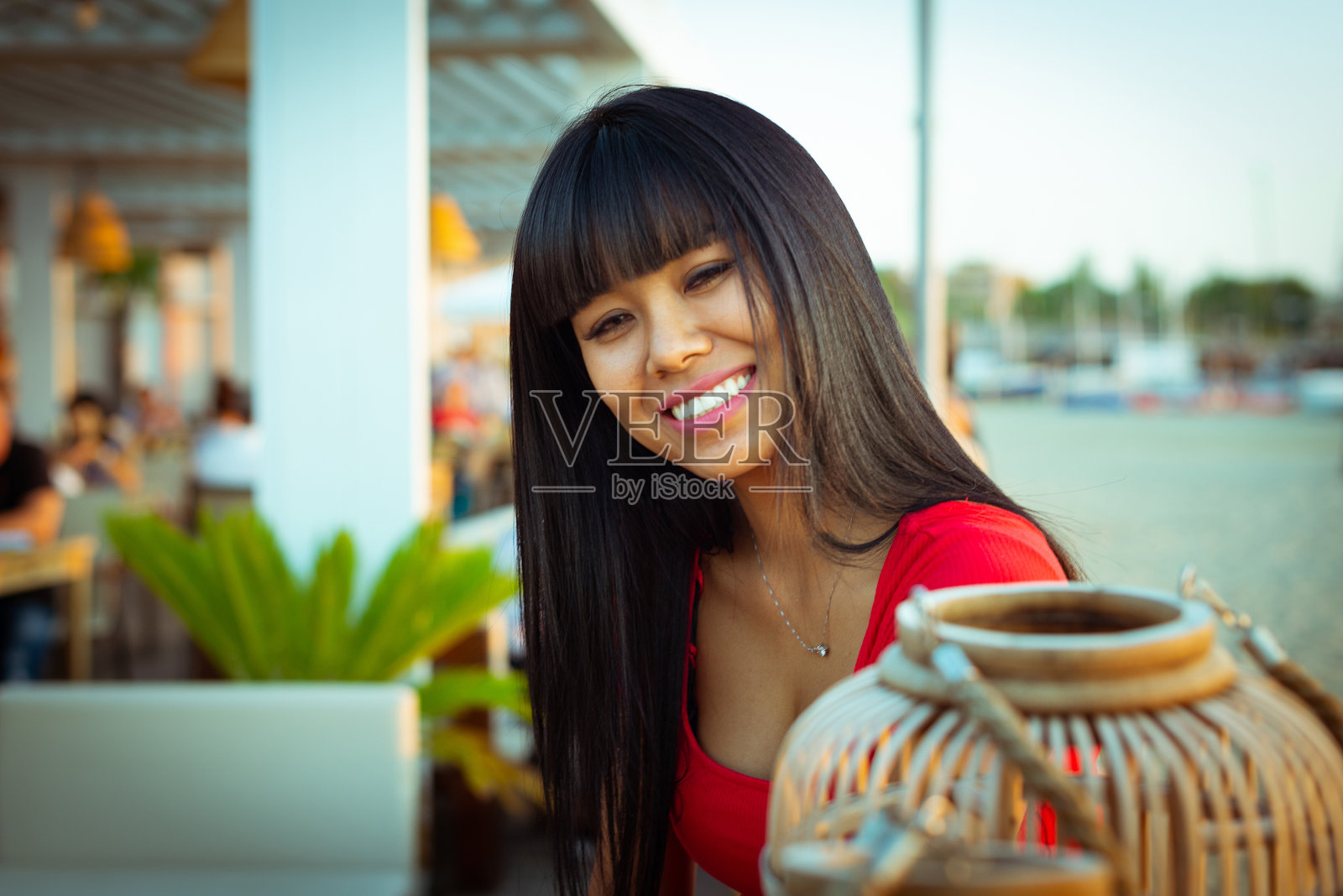 微笑的黑发亚洲女人在海滩上日落在一个休息室酒吧。关于快乐和幸福的概念，花时间在海边的咖啡馆在夏天照片摄影图片