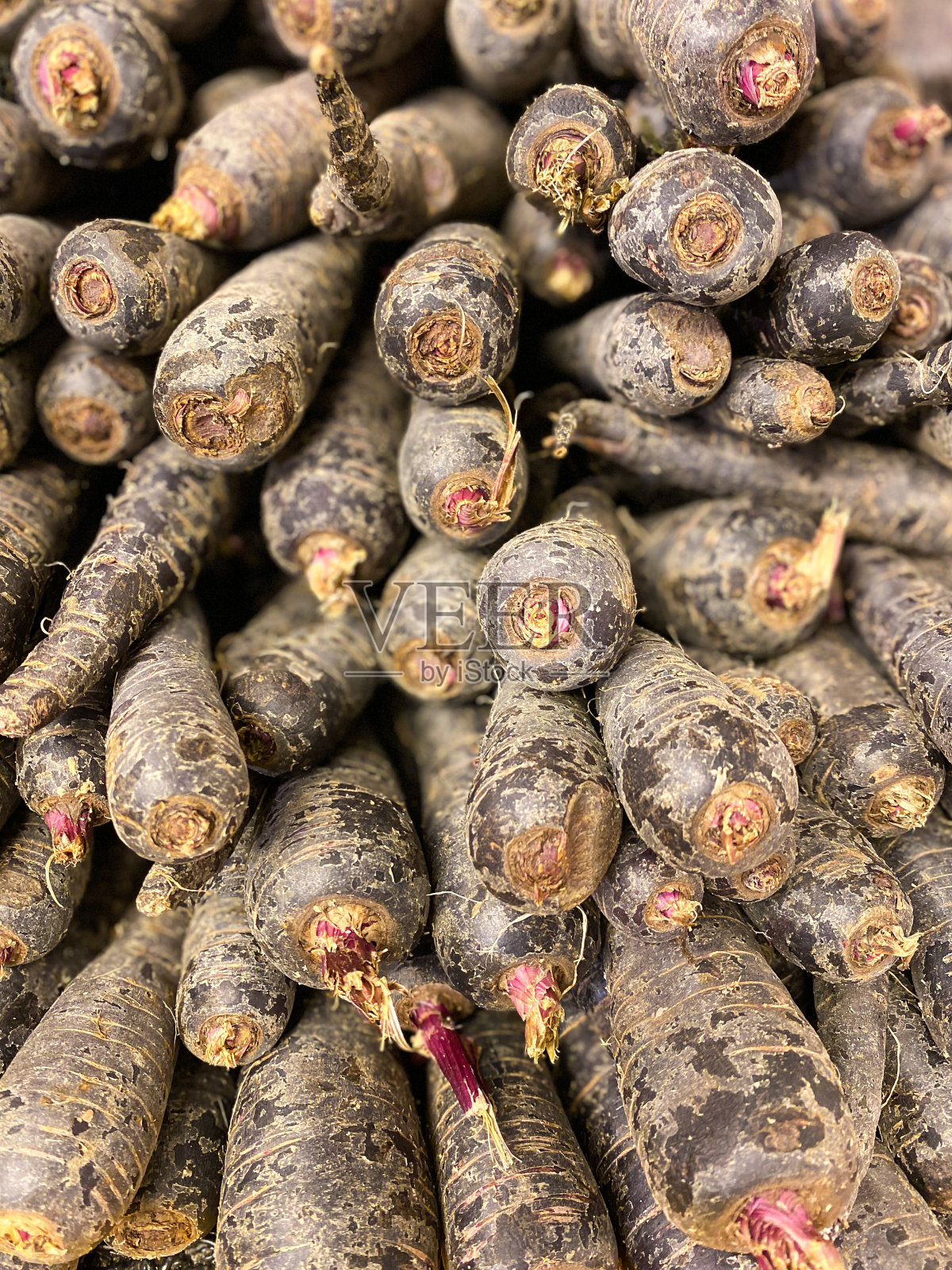 在超市或农贸市场出售的黑色或紫色胡萝卜。照片摄影图片