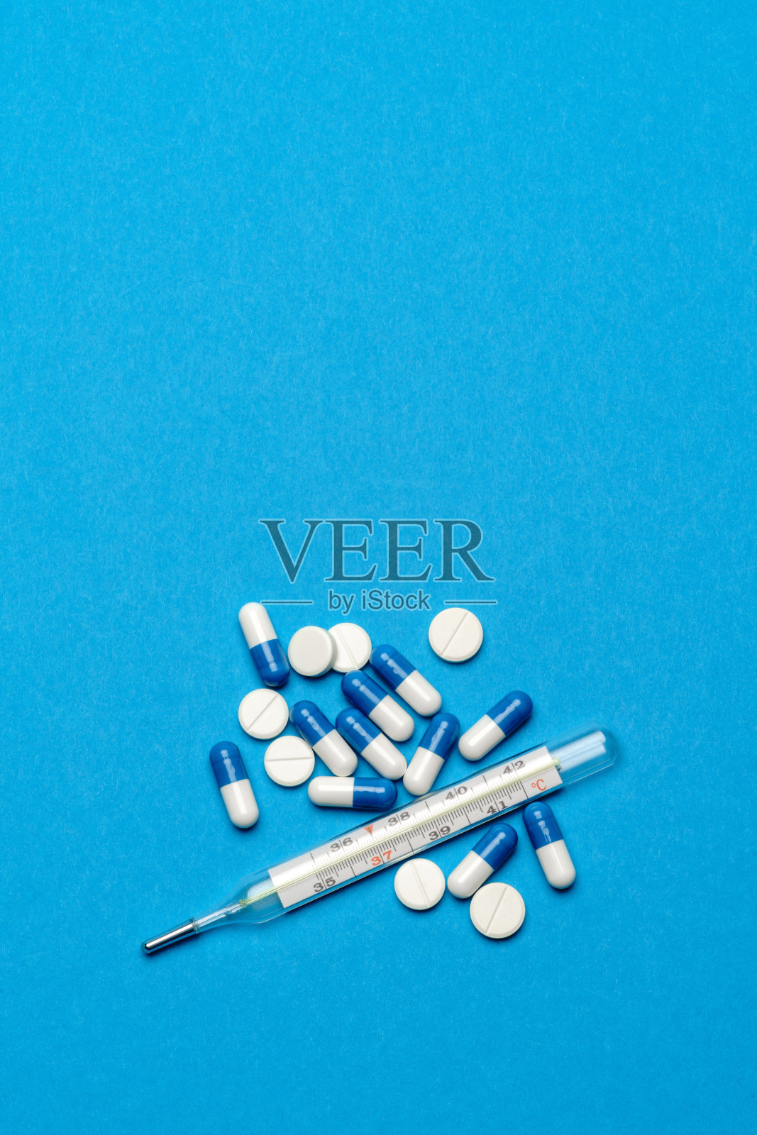 一组白色药丸或片剂，蓝色背景水银温度计照片摄影图片