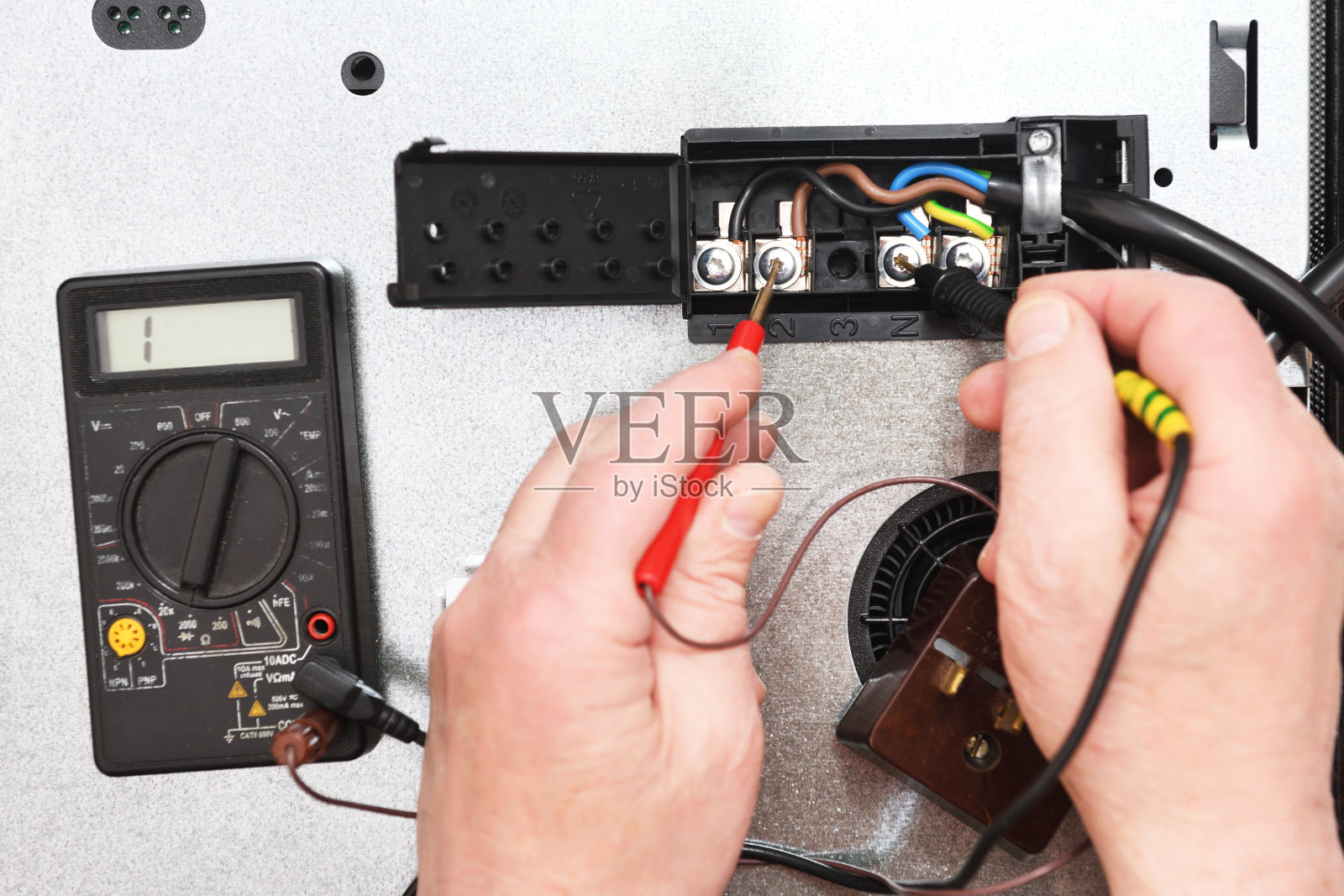 由专业电工用测试仪检查烹饪感应面电路的连接质量、接触点、电压。电炉故障排除。照片摄影图片