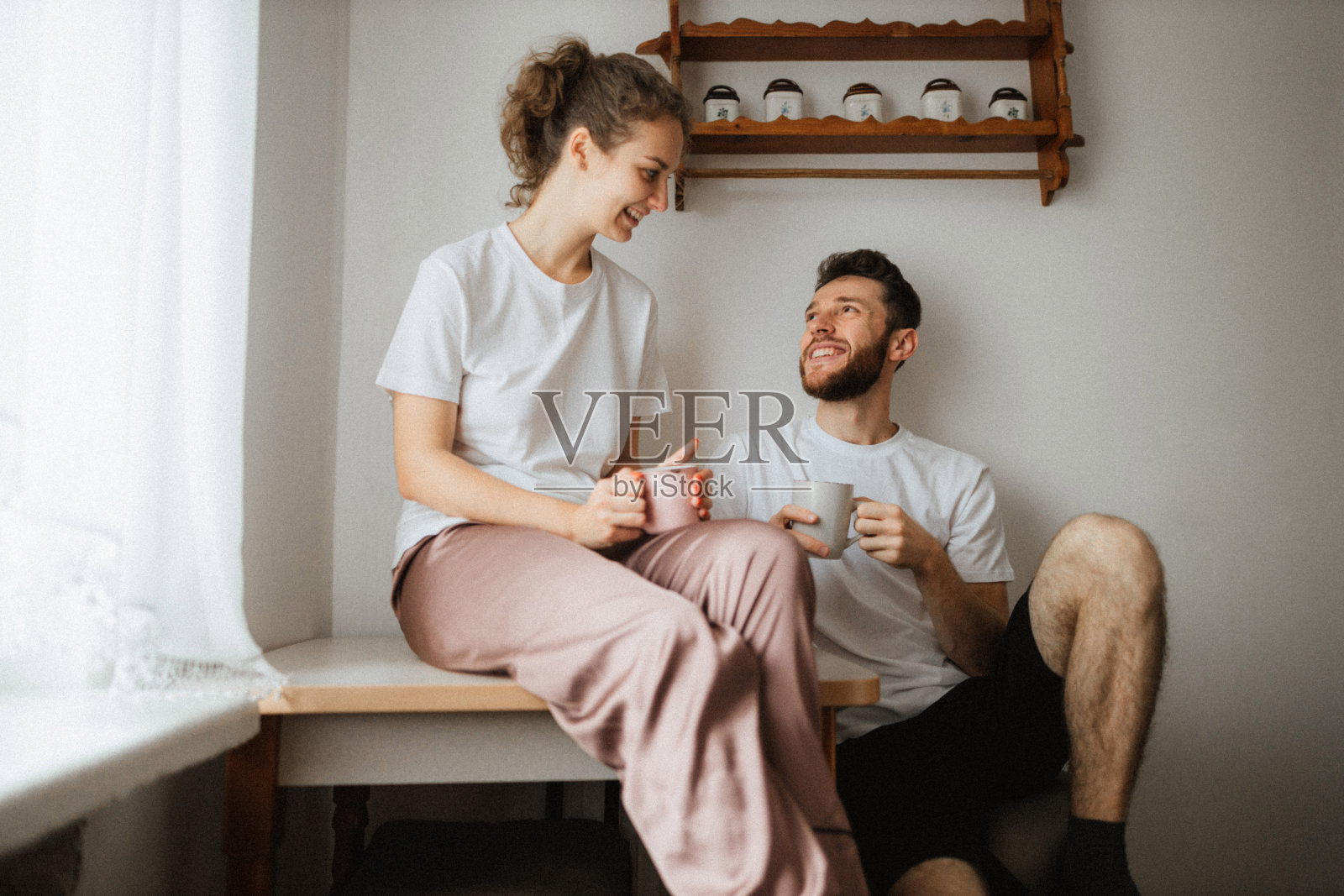 在厨房喝茶或咖啡的年轻快乐夫妇照片摄影图片