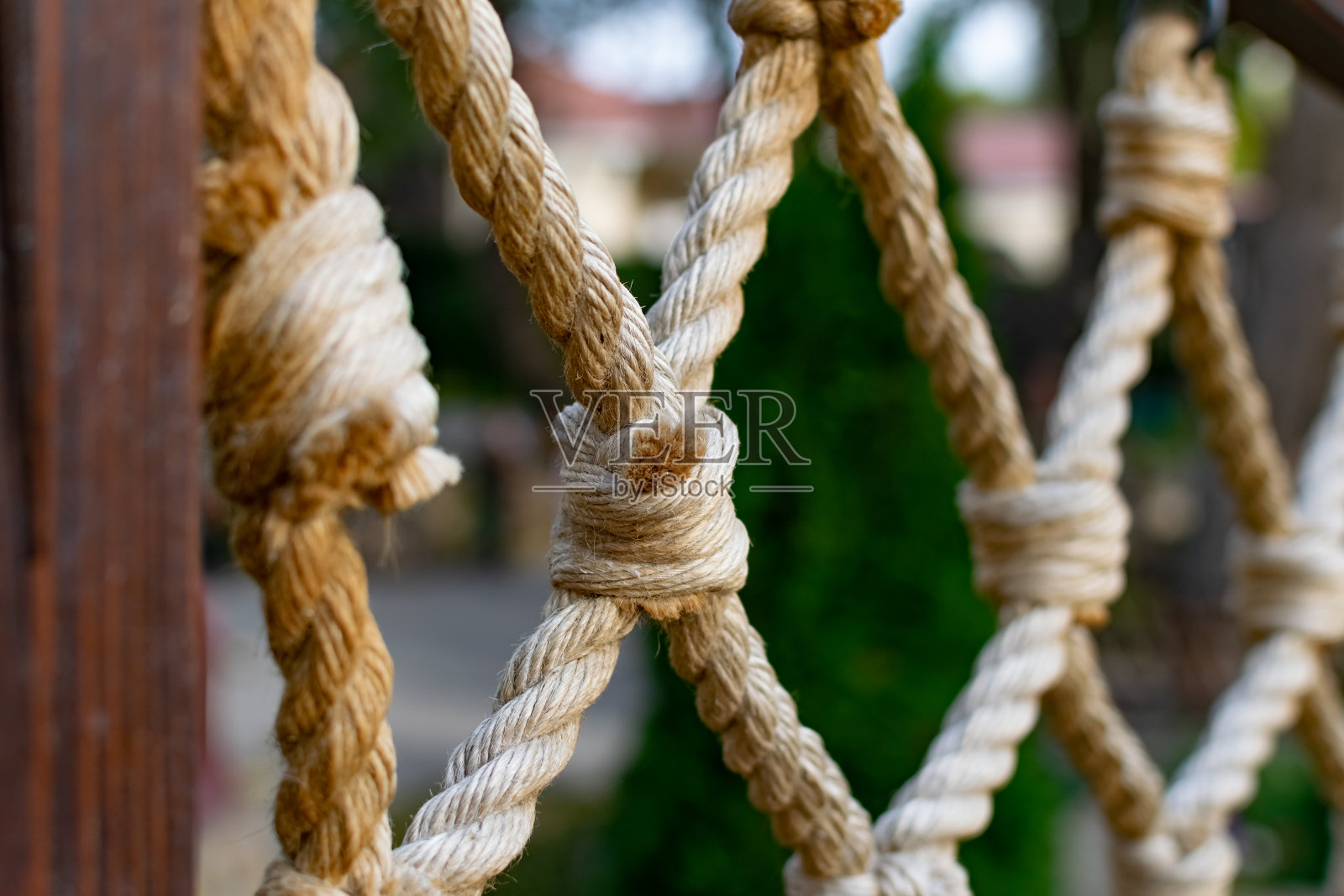 粗绳绳，纵横交错，挂在木栏杆上，装饰围栏沿胡同公园供游憩。照片摄影图片