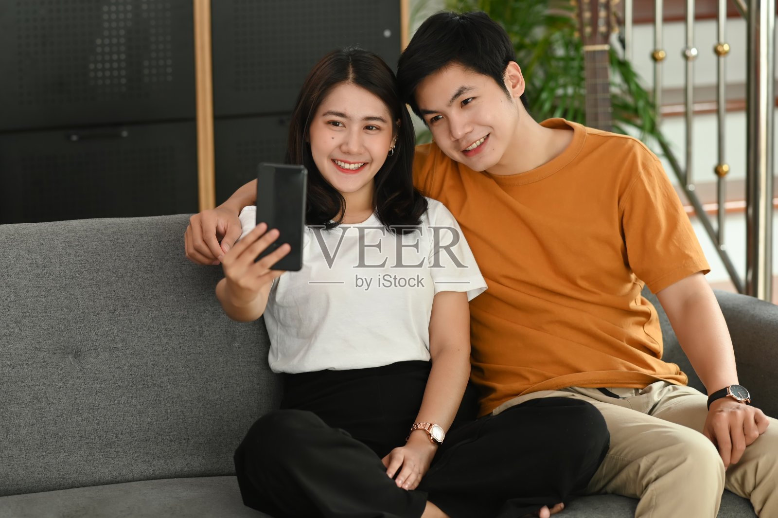 一对快乐的年轻夫妇在客厅的沙发上自拍。照片摄影图片