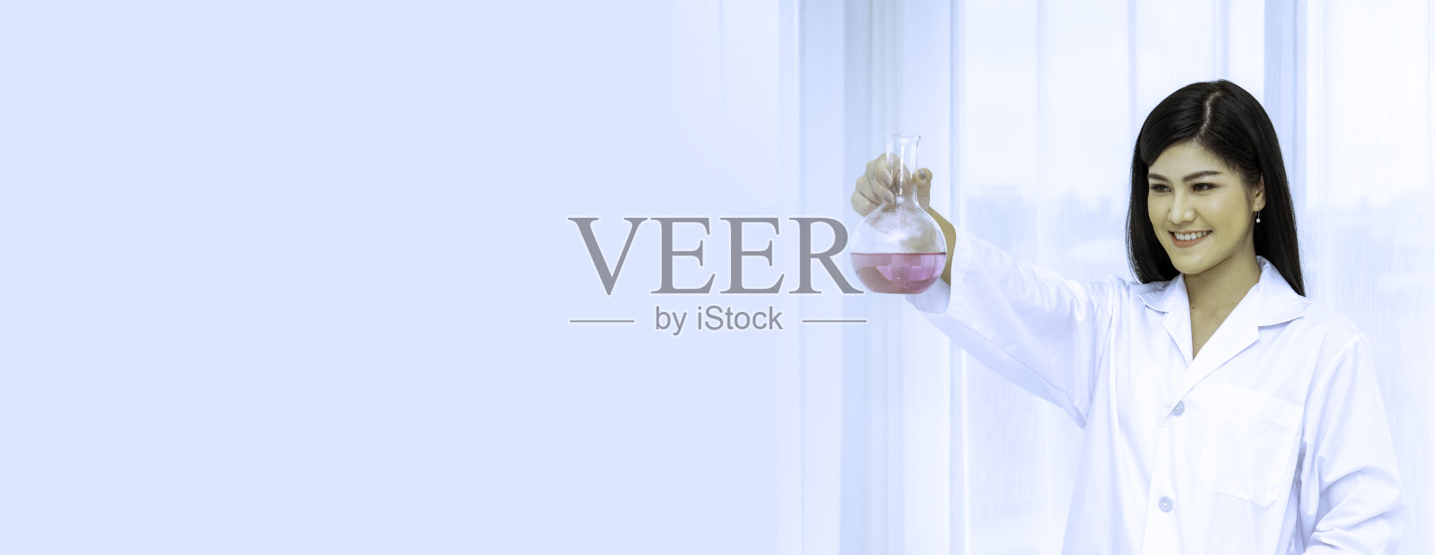 美丽的科学家拿着一个装满紫色溶液的圆底瓶的肖像。照片摄影图片