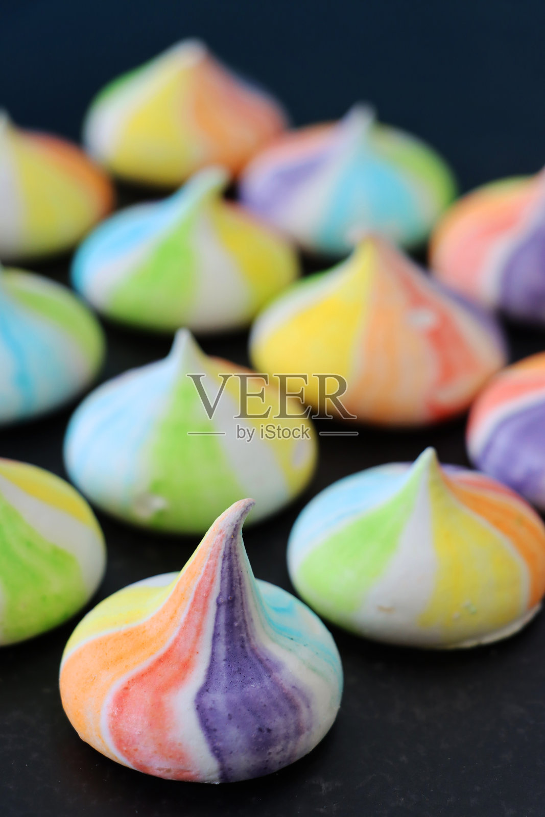 一批微型的，自制的，管道马戏团蛋白酥饼吻，多色彩虹，煮过的蛋白酥饼峰，黑色的背景，关注前景照片摄影图片