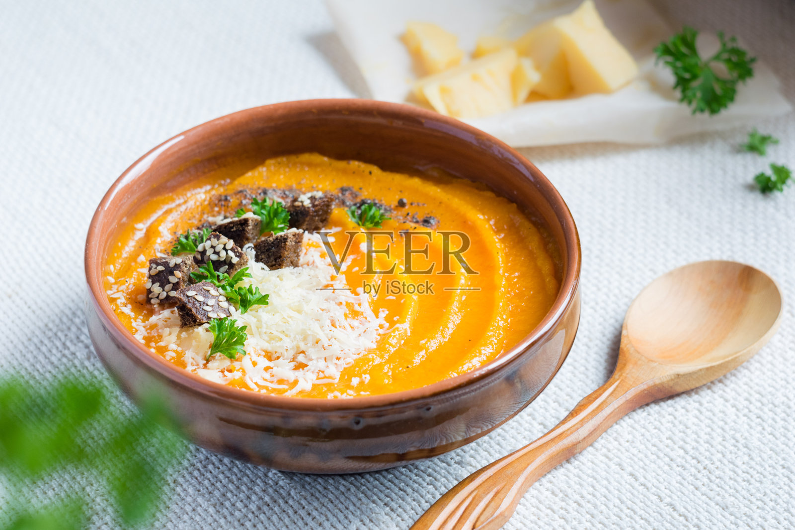 南瓜汤，面包丁，欧芹和磨碎的帕尔马干酪在淡淡的乡村背景，特写照片摄影图片