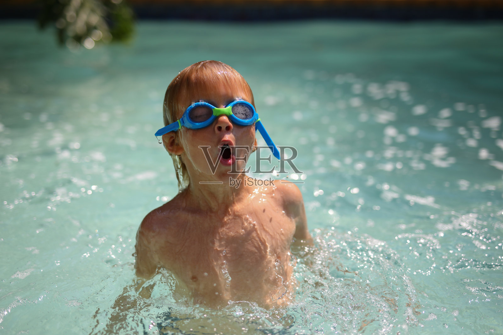 一个小男孩在游泳池里玩。照片摄影图片