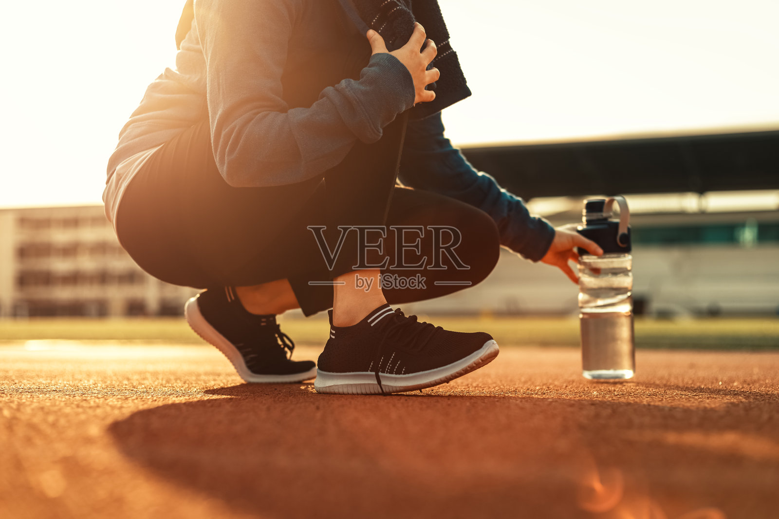 一名女子在户外跑步和体育场内的田径比赛中休息。照片摄影图片