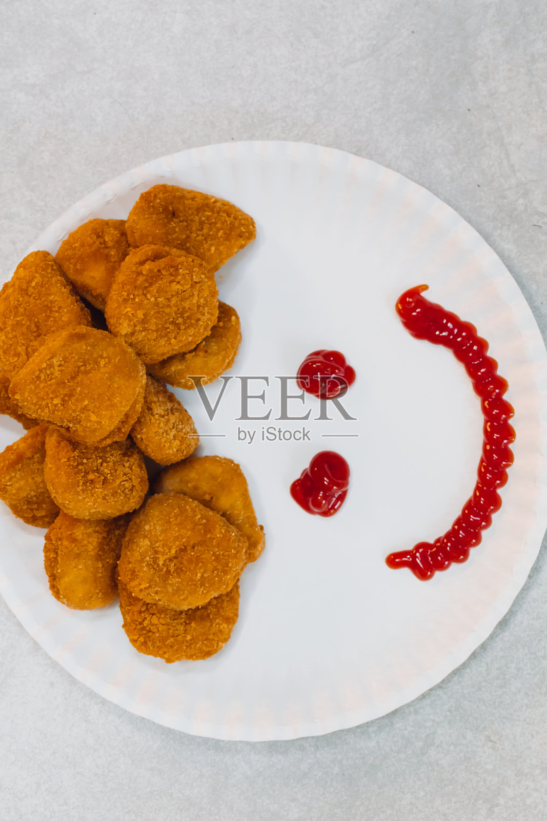 纸盘子里放着鸡块，配上番茄酱，做个笑脸照片摄影图片