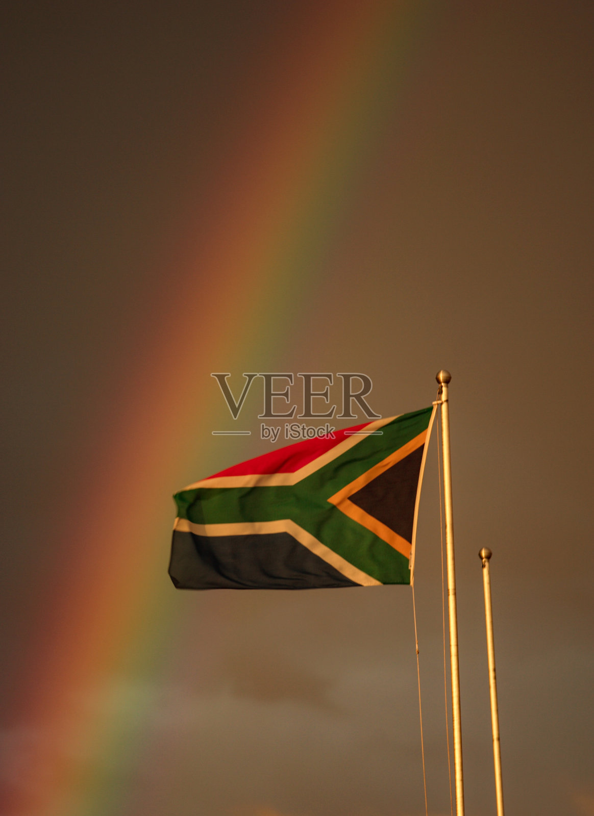 南非国旗在微风中飘扬，背后有一道彩虹。照片摄影图片