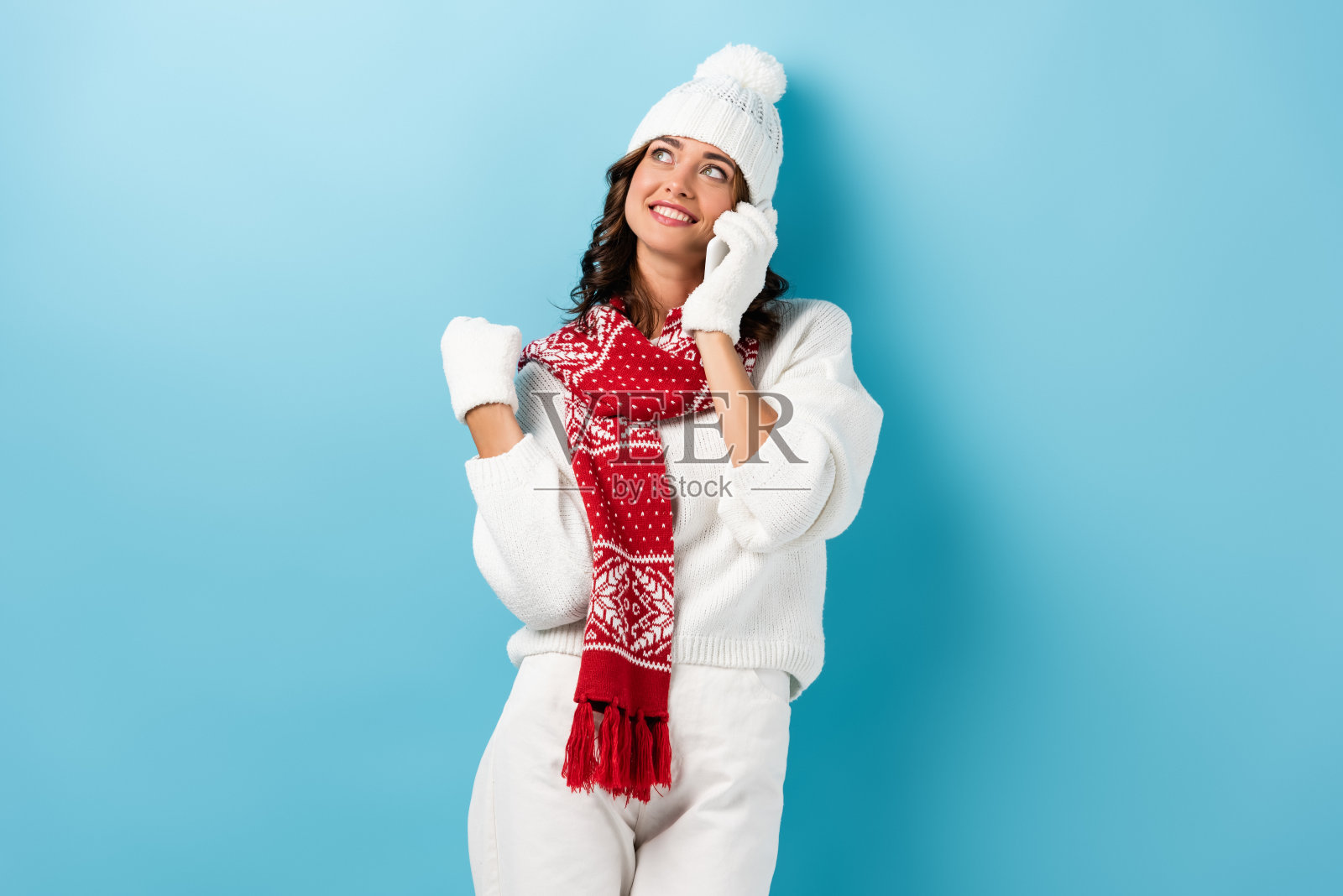 快乐的女人，穿着冬装，抬头用蓝色的智能手机聊天照片摄影图片