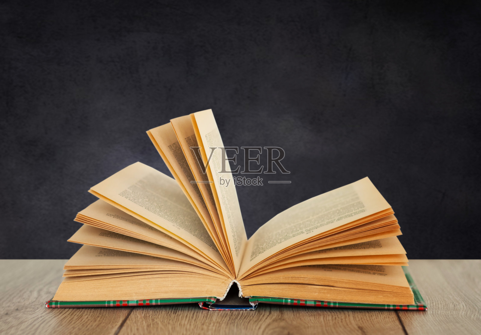 在绿色黑板背景的木桌上打开课本。家庭教育的距离。回到学校，隔离呆在家里的概念照片摄影图片