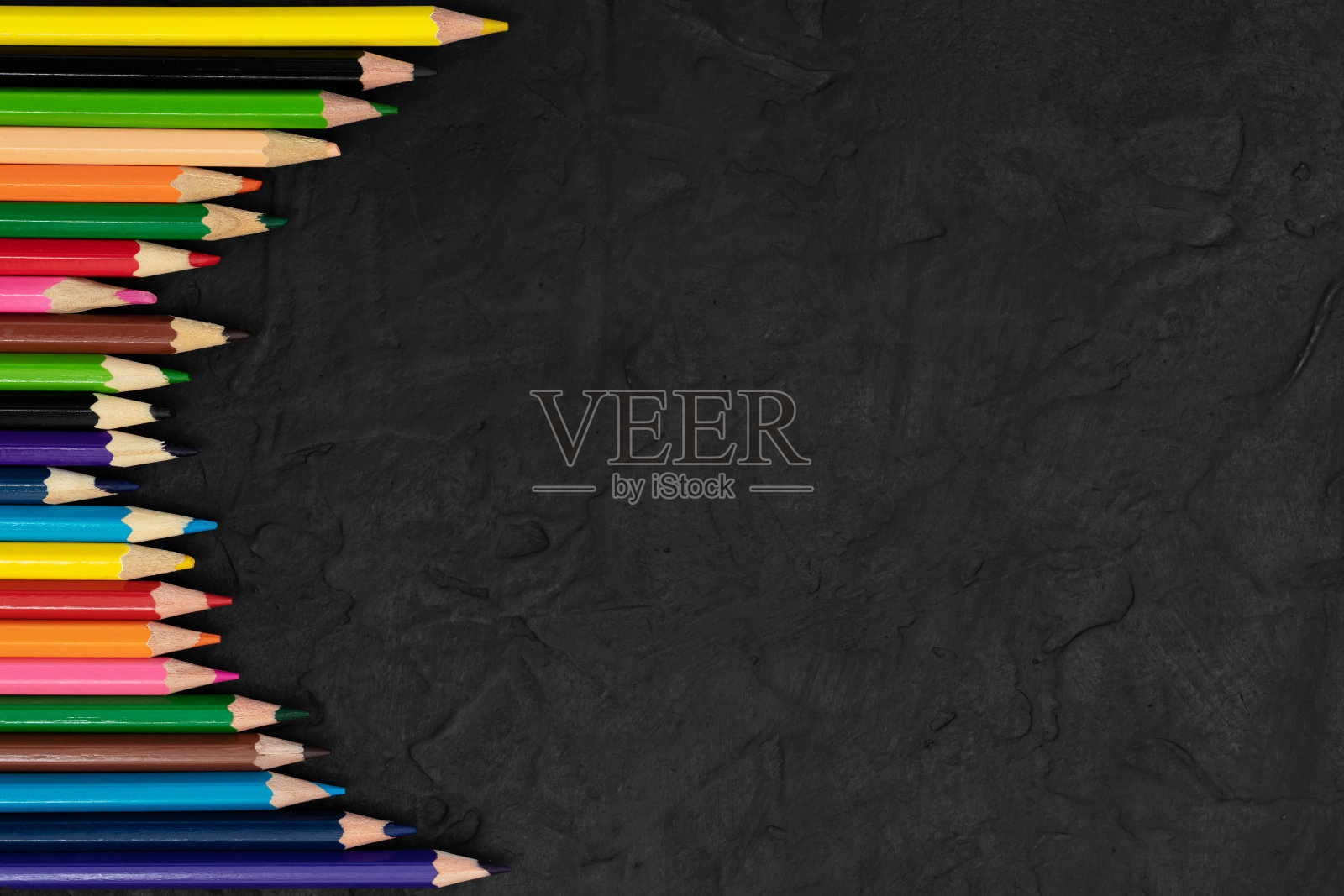 多色铅笔在黑色纹理的背景。照片摄影图片