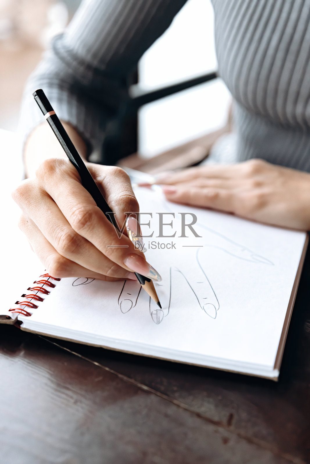 美甲师在一个特制的笔记本上画出指甲设计的草图。美甲师在一个特制的笔记本上画出指甲设计的草图。照片摄影图片