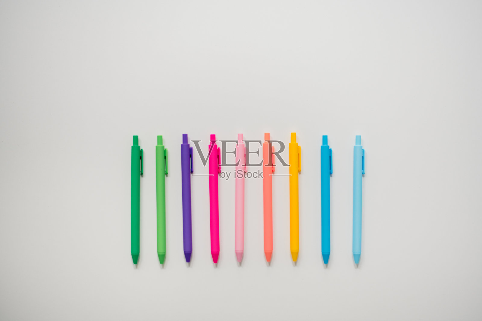 彩色的笔在朴素的白色桌子上一字排开照片摄影图片