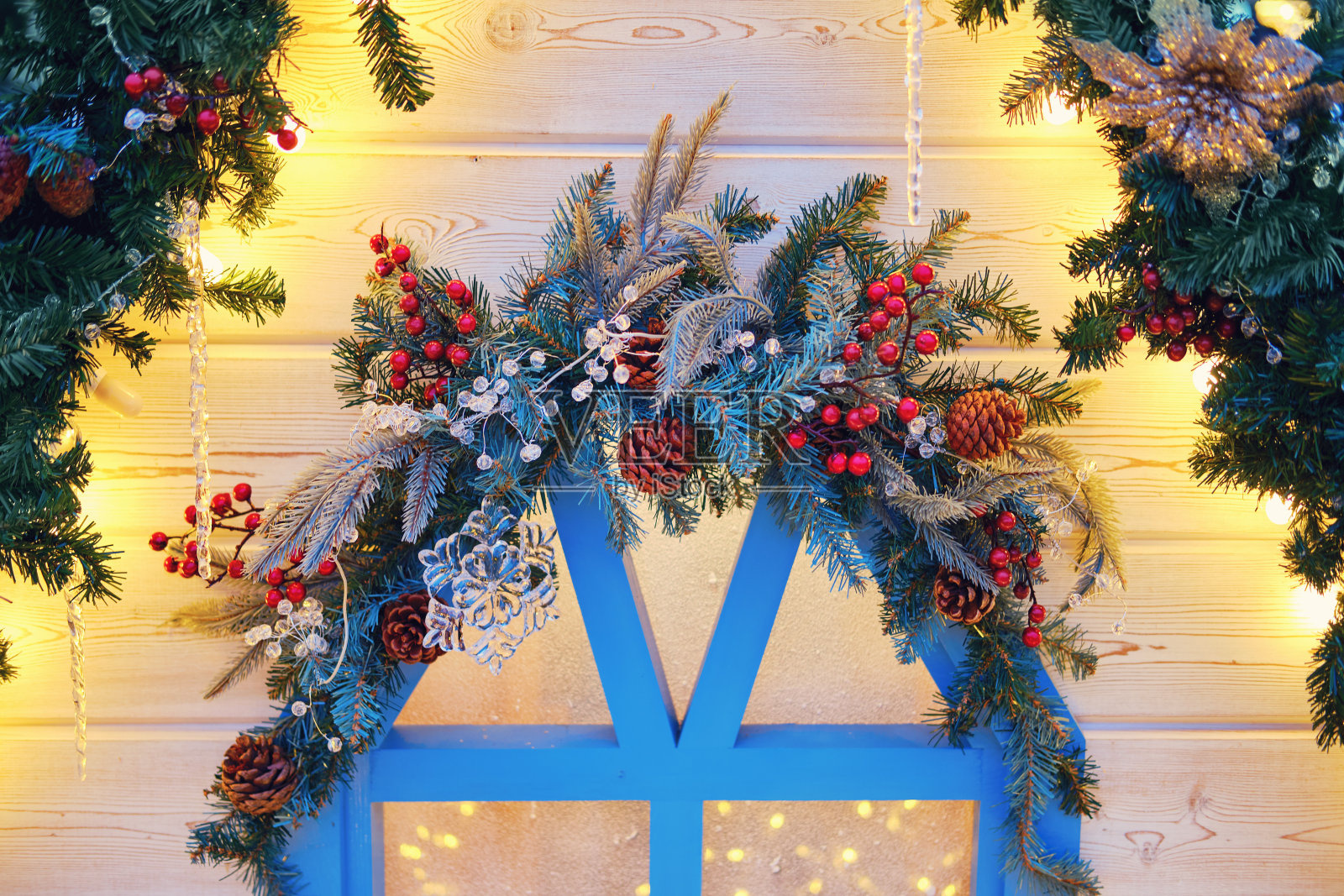 用圣诞树的树枝和槲寄生装饰的木屋的窗户。庆祝新年和圣诞节的装饰品照片摄影图片